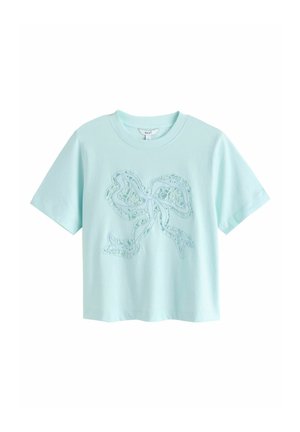 Lyseblå T-shirt med korte ærmer, rund halsudskæring og hæklet sløjfedekoration foran.