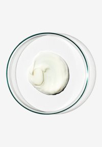 Vispad grädde-liknande konsistens i en klar glasfat, off-white i färgen, med en mjuk och glänsande yta på en vit yta.