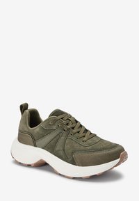 Sněrovací tenisky olivově zelené barvy vyrobené z semiše a tkaniny, s bílou mezipodešví, strukturovanou podešví a designem na šněrování se zátkou.