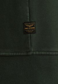 Donkergroene sweatshirt met geribbelde zoom en textuurstof. Voorzien van een zwart en goud "PME Legend" label met een arendontwerp.