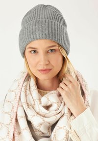 Gray ribbed knit beanie with embroidered butterfly detail, paired with a patterned scarf in white, beige, and pink tones.