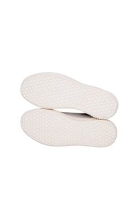 Suole di scarpe in gomma bianca con un motivo a nido d'ape testurizzato e una leggera elevazione. Bordo liscio, design minimalista, senza branding visibile.