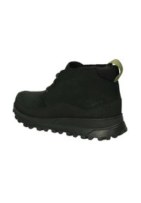 Botas de tobillo de ante negro con suela de goma resistente, cordones redondos y un tirador verde en el talón. Parte superior texturizada, con detalles cerca de la suela.