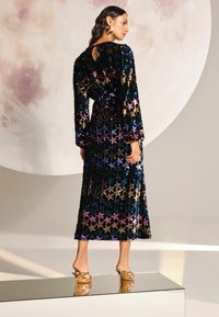 Rochie cu paiete, având o bază neagră, cu modele de stele în auriu, purpuriu și albastru. Mânici lungi, detaliu în formă de cheie la spate și lungime până la podea.