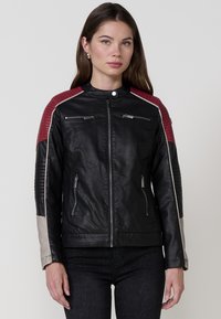 Giubbotto da motociclista in pelle nera con spalle trapuntate rosse e maniche grigie a contrasto. Presenta tasche con zip e colletto alto.
