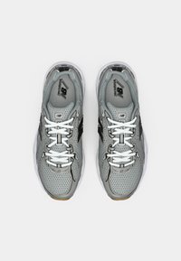 Scarpe da ginnastica grigie realizzate in materiali mesh e sintetici, con lacci bianchi, dettagli neri, un colletto imbottito e una suola testurizzata.