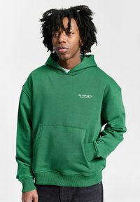 Groene hoodie van een katoenmix, met een voorzak, ribgebreide manchet en kraag, en een "RETERNITY" logo in het wit op de borst.
