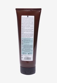 Brun plasttub med ett svart lock. Baksidan har en ljusblå etikett med vit text som detaljerar ingredienser och bruksanvisningar.
