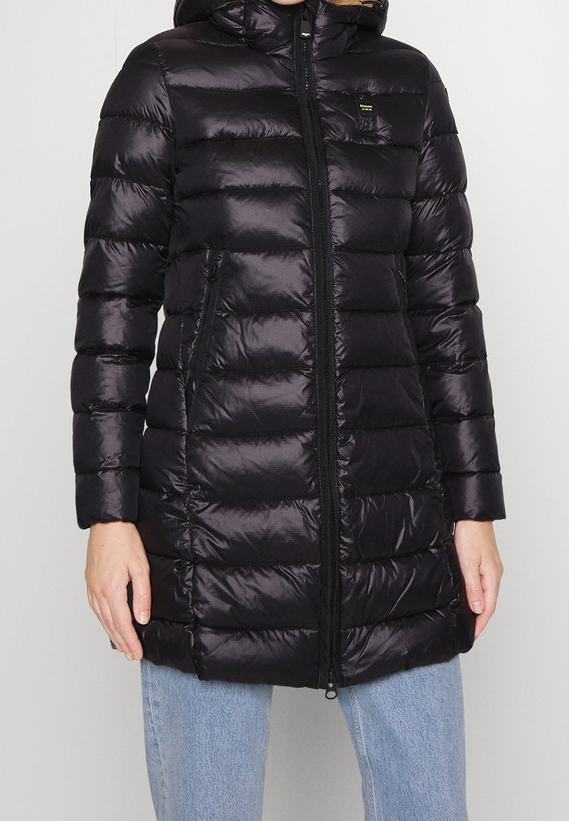 Sort pufferjakke med hætte, der har quiltede sektioner, lynlås lukning og sidelommer. Fremstillet af skinnende, letvægtsmateriale.