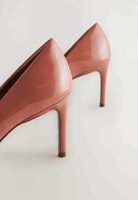Zapatos de tacón alto en material liso de color rosa chicle brillante con puntera afilada y silueta elegante, que cuentan con un delgado tacón de aguja cónico.