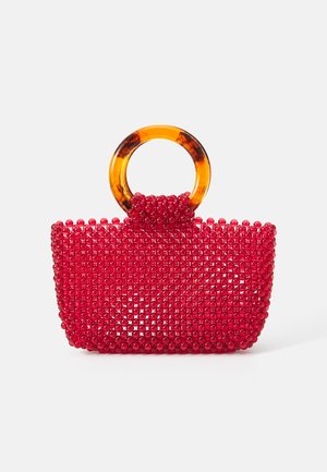 Κόκκινη τσάντα χαντρών με δομημένο σχήμα και διαφανή ακρυλική λαβή. Η επιφάνεια διαθέτει ένα πλέγμα από στρογγυλές χάντρες για υφή και σχέδιο.
