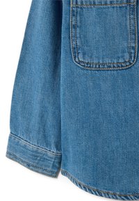 Hellblaues Denimhemd mit langen Ärmeln, Knopfmanschette, kontrastierenden Nähten und einer Brusttasche. Weiche Textur mit sichtbarem Gewebe.