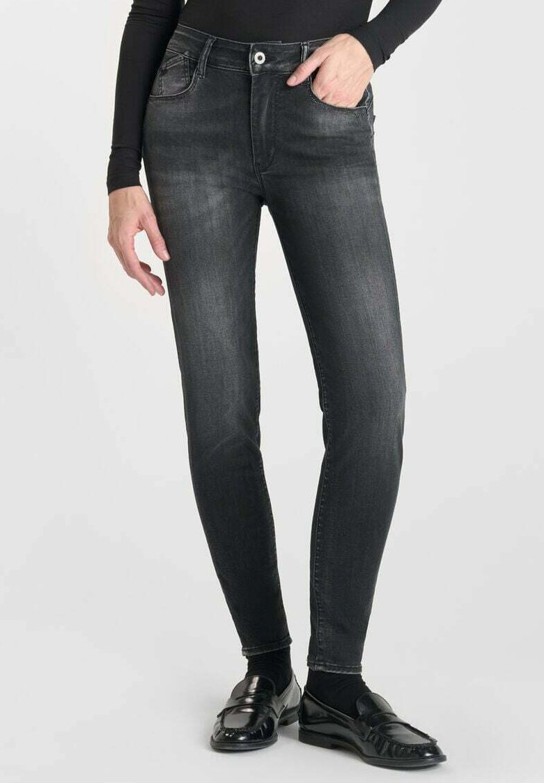 Jean en denim noir avec une coupe slim, cinq poches et un léger délavage. Présente une fermeture à bouton et une finition légèrement texturée.