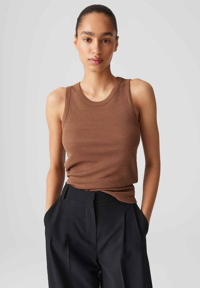 Top in cotone marrone a coste con scollo rotondo e design senza maniche, abbinato a pantaloni neri a vita alta. Tessuto liscio, stile aderente.
