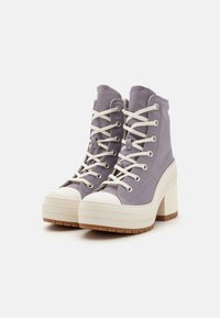 Lila canvas hoge sneakers met een witte rubberen neus en een chunky crème plateauhakken. Voorzien van witte veters en zilveren oogjes.