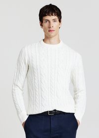 Weißer Pullover mit Zopfmuster, Rundhalsausschnitt und gerippten Bündchen, getragen über marineblauen Hosen. Verfügt über ein durchgängiges strukturiertes Muster.