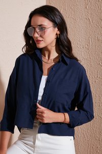 Navy blue cropped button-up shirt in lightweight fabric with long sleeves and a chest pocket, paired with white high-waisted pants.