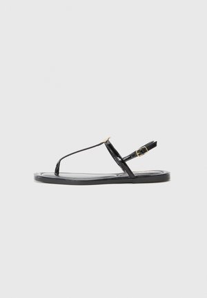 Black patent leather sandals with a T-strap design, adjustable ankle strap, and flat sole. Features a gold-tone buckle accent.