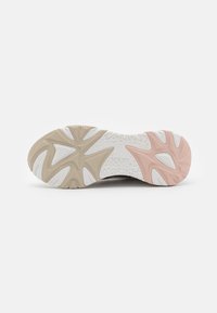 Suola di una sneaker caratterizzata da un design testurizzato con accenti beige terrosi e rosa chiaro, base in gomma bianca e modelli di trazione prominenti.