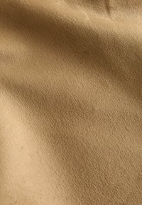 Hnedá tkanina s jemnou, hladkou textúrou, s miernym leskom. Tenké variácie farby naznačujú mäkký, plyšový povrch.