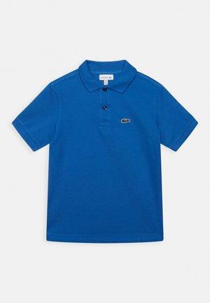 Blå kortærmet poloshirt med to knapper og et lille grønt krokodillelogo på brystet, lagt fladt på en hvid baggrund.