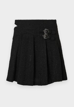 Melnas vilnas svārki ar strukturētu jostasvietu, plecu dizainu un divām dekoratīvām sprādzēm priekšpusē. Tekstūra audums ar smalku spīdumu.