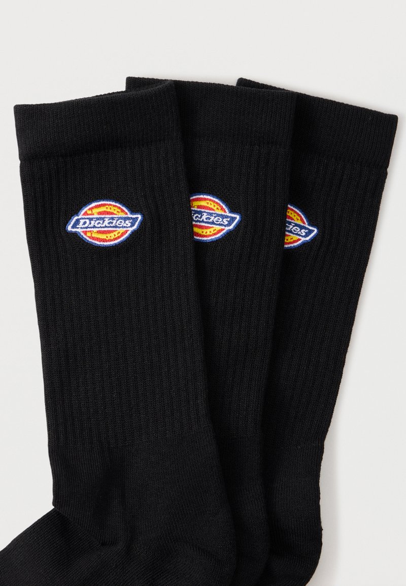 Three black ribbed crew socks with a colorful Dickies logo patch near the top cuff, arranged in overlapping rows.
