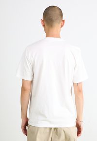 T-shirt bianco in cotone con maniche corte e scollatura rotonda classica, mostrato da dietro, che rivela una texture liscia e una vestibilità casual.