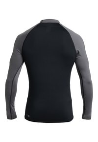 Chemise de sport à manches longues avec un corps noir et des manches grises. Fabriquée en matériau extensible avec une texture lisse et des coutures plates.