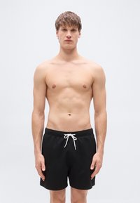 Μαύρα μαγιό βερμούδα με υφή στο ύφασμα, ελαστική ζώνη και λευκό κορδόνι, μήκος μέχρι το μέσο του μηρού και χωρίς ορατά σχέδια.