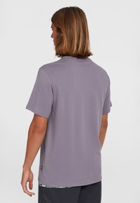 Lyse lilla kortærmet t-shirt i et blødt stof, med rund hals og et lille mærke nederst. Enkel og afslappet pasform.