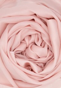 Tessuto di seta rosa chiaro disposto in un motivo a spirale, che mette in mostra una consistenza liscia e una morbida lucentezza. Nessun hardware o accento visibili.