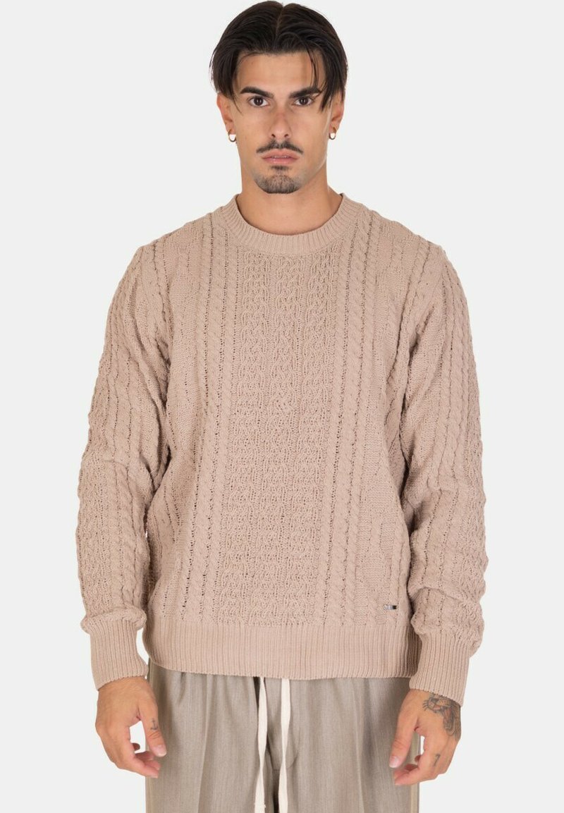 Maglione beige a maglia con un motivo testurizzato caratterizzato da evidenti design a trecce, un colletto rotondo e polsini e orlo a coste.