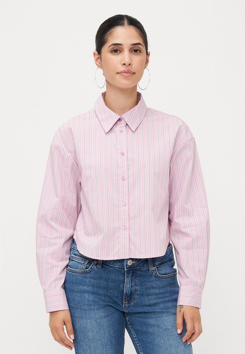 Cropped pink shirt with vertical white stripes, button-up front, large collar, and long sleeves with striped cuffs. Paired with blue jeans.