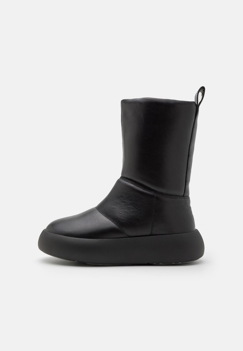 Bottines en cuir noir avec un bout arrondi, une texture lisse, une semelle épaisse et une languette à l'arrière pour un enfilage facile.