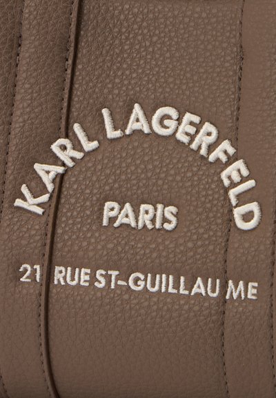 Кафява текстурирана кожа с бял бродиран текст, който гласи "KARL LAGERFELD PARIS 21 RUE ST-GUILLAUME."