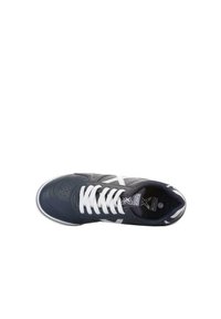 Zapatilla negra con cordones blancos, que presenta una parte superior de cuero liso y detalles perforados. Logo acentuado en la lengüeta y el lateral.