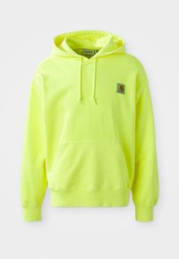 Neon yellow hoodie made of cotton. Features a front pocket, drawstring hood, and a small logo patch on the upper left side. Soft texture.