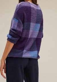 Purple and blue checkered sweater in soft, textured fabric; features rolled sleeves and a relaxed fit, visible from the back.
