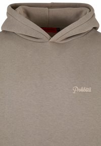 Haut à capuche beige clair en tissu doux, doté d'une capuche avec cordon de serrage et d'un petit logo "Interdit" en rose pâle sur la poitrine.