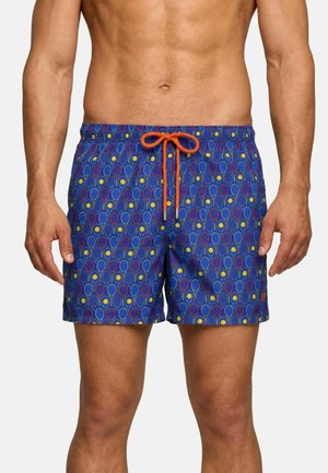 Uomo che indossa pantaloncini da bagno blu con motivo di racchette da tennis colorate e palline da tennis gialle, legati con un cordoncino arancione.