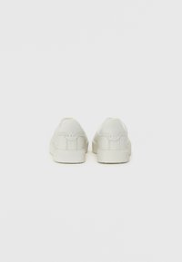 Sneakers bianchi con una texture liscia, design a bassa altezza e styling minimalista. Presentano motivi di cucitura discreti e una suola piatta in gomma.