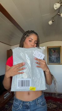 Felpa grigia in confezione trasparente, con un'etichetta contenente dettagli e un codice a barre. È applicato un vivace adesivo giallo.