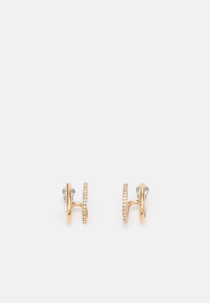 Paire de boucles d'oreilles créoles dorées avec une boucle lisse et une boucle incrustée de petits cristaux clairs, présentées sur fond blanc.