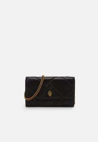 Black quilted leather clutch with gold chain strap and ornate gold hand-shaped clasp on white background.