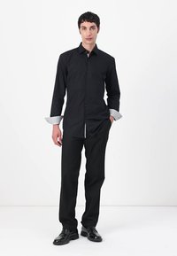 Black dress shirt with long sleeves, button placket, and contrasting white-collared cuffs. Worn with black trousers and shoes.