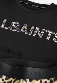 Svart bomullströja med upphöjda leopardtryckbokstäver "ALLSAINTS" och "LONDON" präglade i svart på nederkanten.