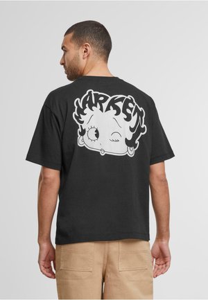 Svart bomulls-T-skjorte med et stort hvitt tegneseriegraphikk av en karakter som blunker på baksiden, rund hals og korte ermer.