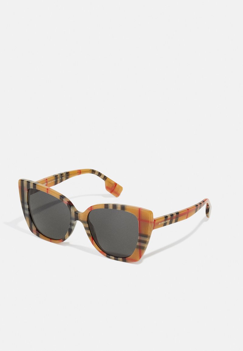 Óculos de sol em formato de gato com um padrão xadrez em laranja, preto e amarelo. Lentes escuras e armações de plástico estruturadas e brilhantes.