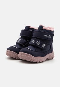 Jūras spēku ziemas zābaki ar rozā vilnas oderi, diviem Velcro siksniņām, sniegpārsliņu akcentiem un strukturētām gumijas zālēm, lai nodrošinātu saķeri.